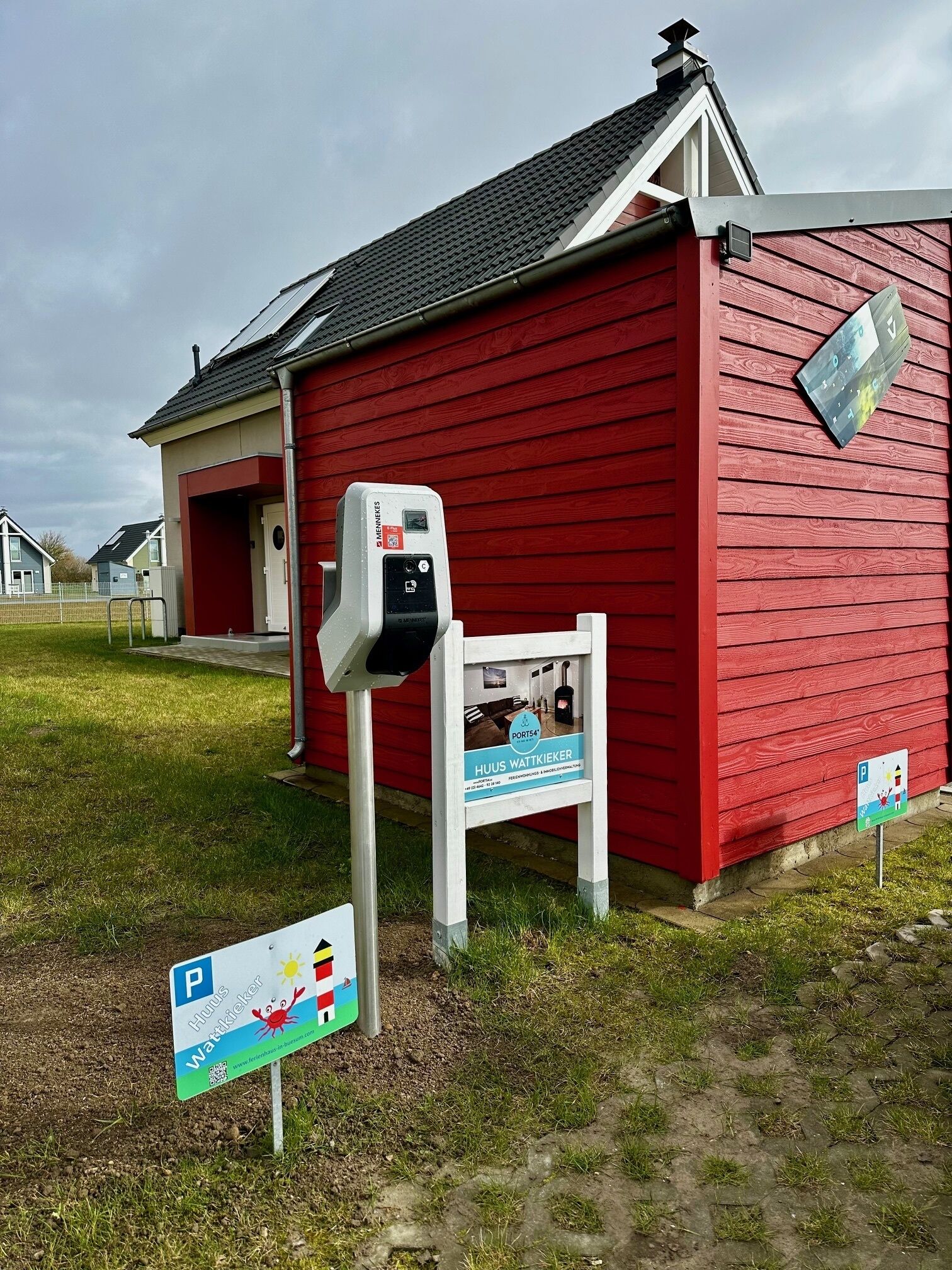 A red building with a mailbox and a sign indicating a parking area.