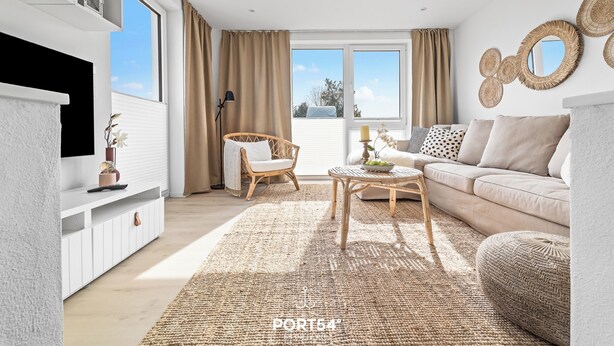 A modern living room with a sofa, coffee table, and a TV on a white cabinet. - Meerliebe – sea view, roof terrace, infrared sauna, shower, EV charging station (Glücksburg)