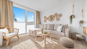 A modern living room with a sofa, two chairs, a coffee table, and a large window. - Meerliebe – sea view, roof terrace, infrared sauna, shower, EV charging station (Glücksburg)