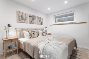 A modern bedroom with a bed, bedside tables, and wall art. - Meerliebe – sea view, roof terrace, infrared sauna, shower, EV charging station (Glücksburg)