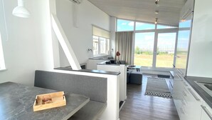 Eine moderne Küche mit Essbereich, großen Fenstern und Blick ins Freie.