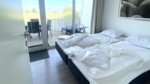 Ein Hotelzimmer mit einem großen Bett, einem Balkon mit Sitzgelegenheit und Blick auf die Landschaft.