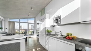 Eine moderne Küche mit weißen Schränken, einer eingebauten Mikrowelle und einer Edelstahl-Spüle.
