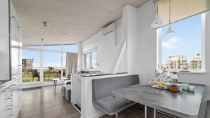 A modern kitchen with a dining area, large windows, and a view of buildings. - Ferienhaus Sonnenblume Marina Wendtorf (Wendtorf)