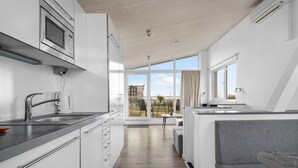 A modern kitchen with a built-in oven, a sink, and a window overlooking a balcony. - Ferienhaus Sonnenblume Marina Wendtorf (Wendtorf)