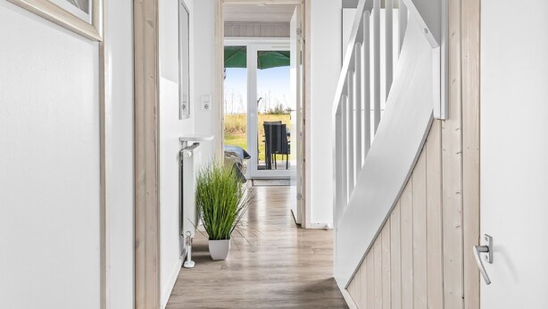 A modern interior with a wooden floor, white walls, and a staircase leading to an outdoor area. - Ferienhaus Sonnenblume Marina Wendtorf (Wendtorf)