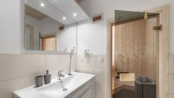 A modern bathroom with a white sink, mirror, and wooden door.