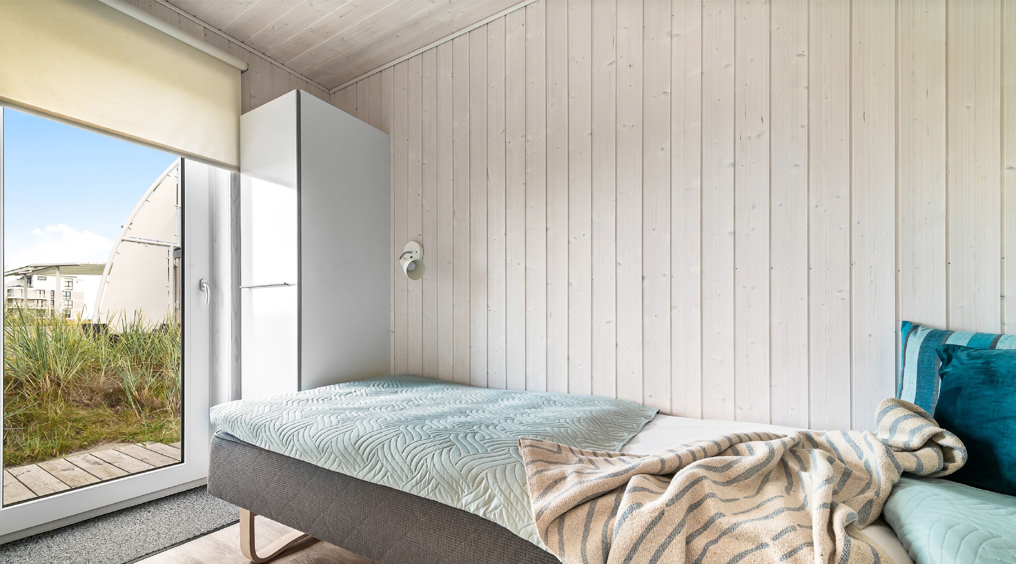 A bedroom with a bed, a window, and a door.