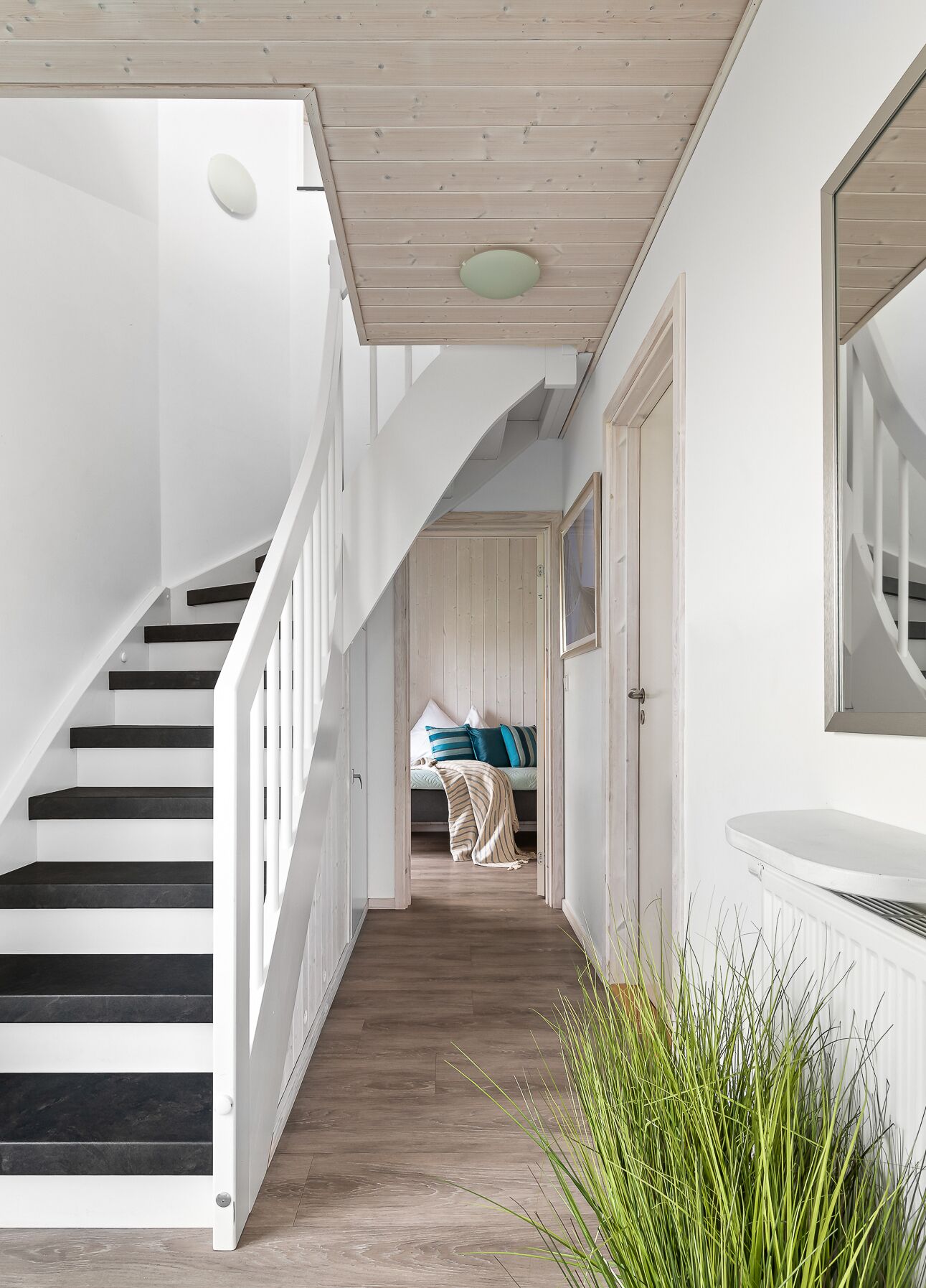 Un escalier menant à une chambre à coucher équipée d’un lit, d’une table de chevet et d’un miroir.
