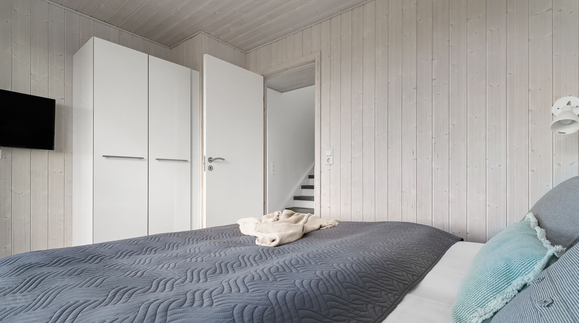 Une chambre à coucher avec un lit, une télévision et une armoire.