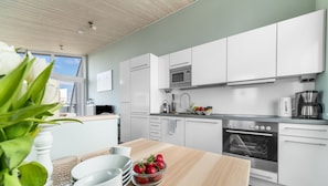 A modern kitchen with white cabinets, a built-in oven, and a coffee maker.
