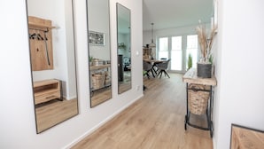 Ein modernes Interieur mit Holzboden, einer Essecke mit Tisch und Stühlen sowie einem großen Spiegel an der Wand.