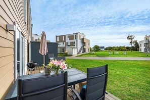 A patio with outdoor furniture, a grill, and a table with flowers.
