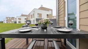 Ein Essbereich im Freien mit einem Tisch für zwei Personen, einem Blumenstrauß und Weingläsern.