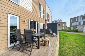 A modern outdoor patio with a table and chairs, a covered seating area, and a view of neighboring buildings. - Hollywood Lounge - Infrared Sauna, Fireplace, Parking Space, EV Charging Station (Olpenitz)