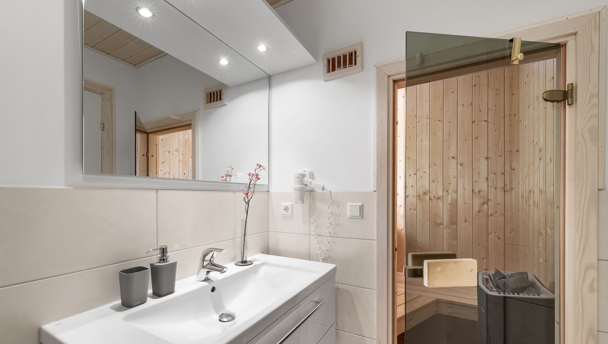 Ein modernes Badezimmer mit einem weißen Waschbecken, einem Spiegel und Holzwandverkleidungen.