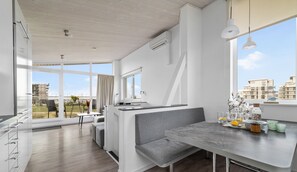 Eine moderne Küche mit einer grauen Küchenzeile, einem Esstisch und Blick auf die Stadt.