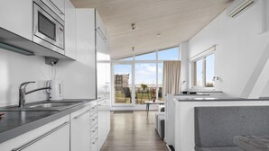 Een moderne keuken met een ingebouwde oven, een koffieapparaat en een spoelbak. Er is een balkon met uitzicht op de stad.