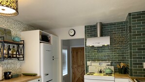 A kitchen with a white refrigerator, a stove, and a clock on the wall. - Adorable Cottage in National Forest -- hiking & climbing steps from your door! (Dumont)
