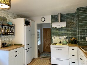 Una cocina con un refrigerador blanco, una estufa y un reloj en la pared.