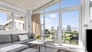 Un soggiorno moderno con un divano grigio, un tavolino da caffè e vista su un balcone con mobili da esterno.