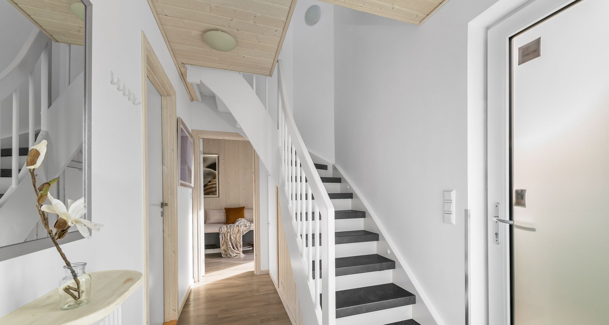 Ein modernes Interieur mit einer Treppe, einer Tür und einem Flur, der zu einem Schlafzimmer führt.