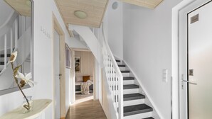 Un interno moderno con una scala, una porta e un corridoio che conduce a una camera da letto.