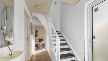 Ein modernes Interieur mit einer Treppe, einer Tür und einem Flur, der zu einem Schlafzimmer führt.