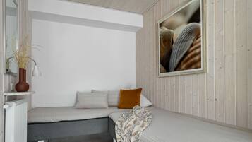 Quarto minimalista com cama, mesa de cabeceira com abajur e espelho.