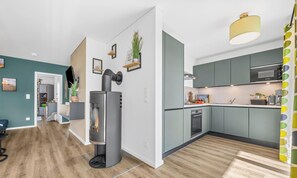 A modern kitchen with grey cabinets, a Bosch microwave, and a wood-burning stove.