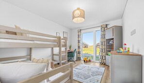 A child's bedroom with bunk beds, a desk, toys, and a view of a garden. - Tüddelbüddel - Infrared Sauna, Bathtub, Fireplace, Terrace, Grill, Parking (Olpenitz)