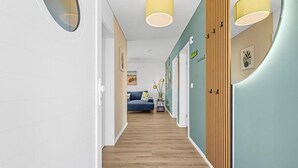 En hall med trägolv, en blå soffa och en klädhängare som är monterad på väggen.
