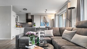A modern living room with a grey sofa, a coffee table with a vase of flowers, and a painting on the wall. - Ferienhaus Hannes Büsum (Büsum)