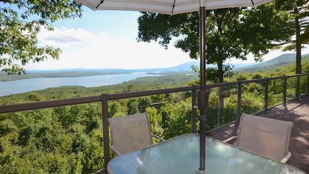 A balcony with a glass table and chairs, overlooking a lake and forested landscape. - Unequalled Views of Reservoir & Mtns, Affordable, Totally Private (West Hurley)