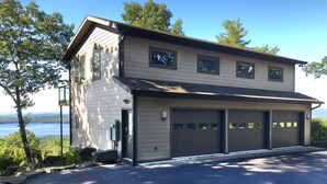 A two-story house with a garage, a visible outdoor area, and a view of a body of water. - Unequalled Views of Reservoir & Mtns, Affordable, Totally Private (West Hurley)