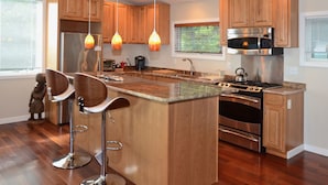 A modern kitchen with wooden cabinets, stainless steel appliances, and a central island with bar stools. - Unequalled Views of Reservoir & Mtns, Affordable, Totally Private (West Hurley)