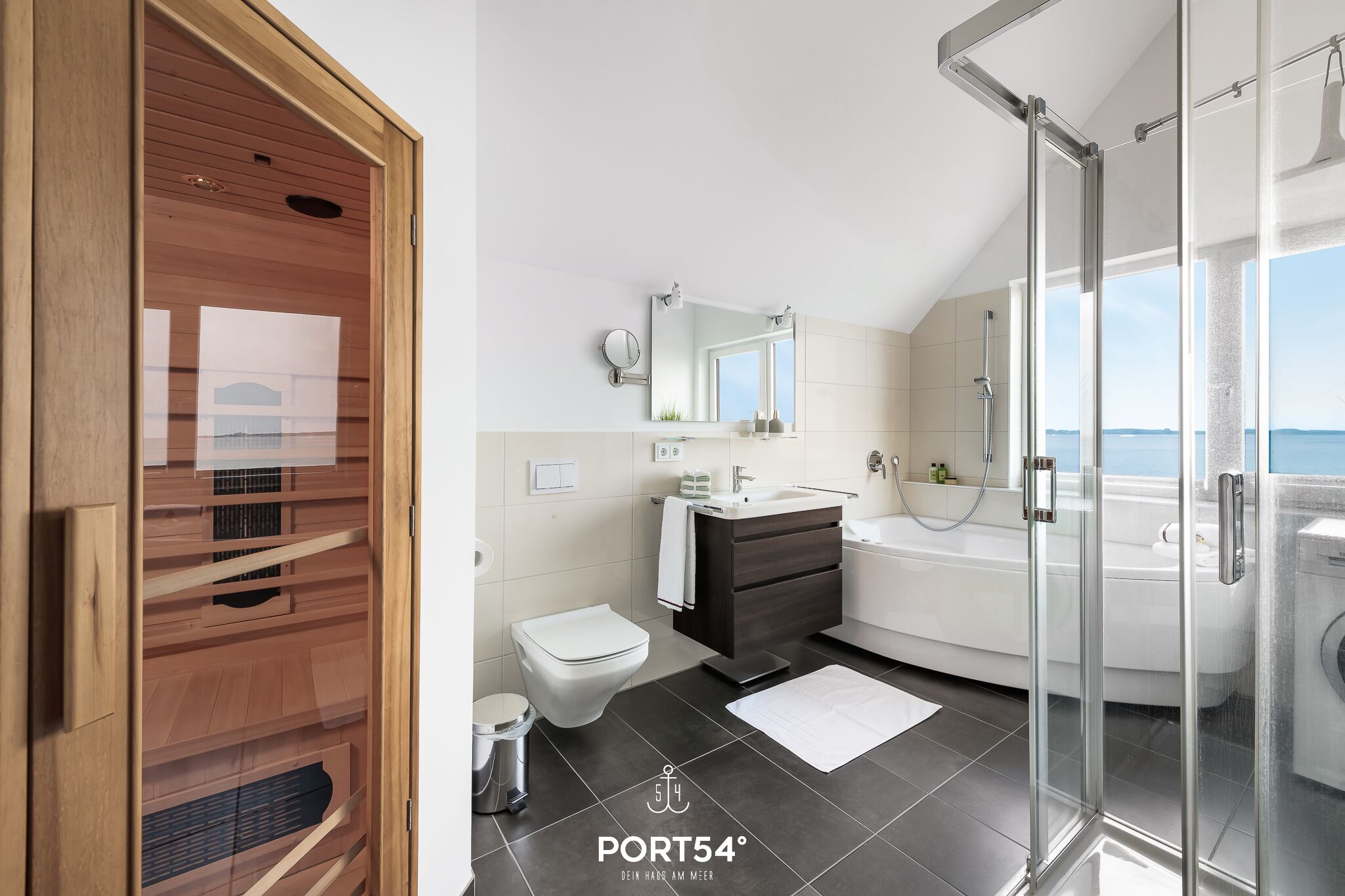 A modern bathroom with a glass shower enclosure, a white toilet, a dark wooden vanity, and a large bathtub.