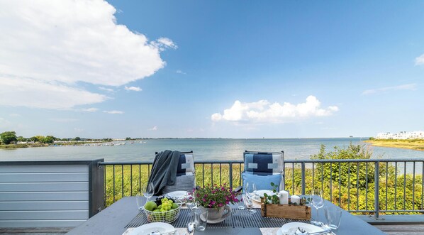Une table dressée pour deux personnes, avec vue sur l’eau et les bâtiments situés au loin.