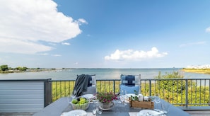 A table set for two with a view of the water and distant buildings.