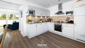 A modern kitchen with white cabinets, a wooden countertop, and stainless steel appliances. - Fjordblick– first row on the water, sauna, whirlpool, shower, fireplace, balcony (Olpenitz)