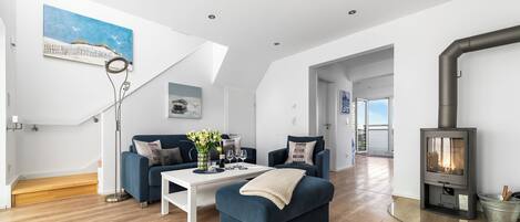 A modern living room with a blue sofa, white coffee table, and a wood-burning stove.