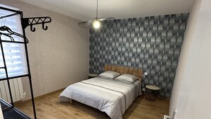 Et soveværelse med seng, pendel, radiator og skab.