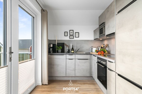 A modern kitchen with a large window, a built-in oven, and a microwave.