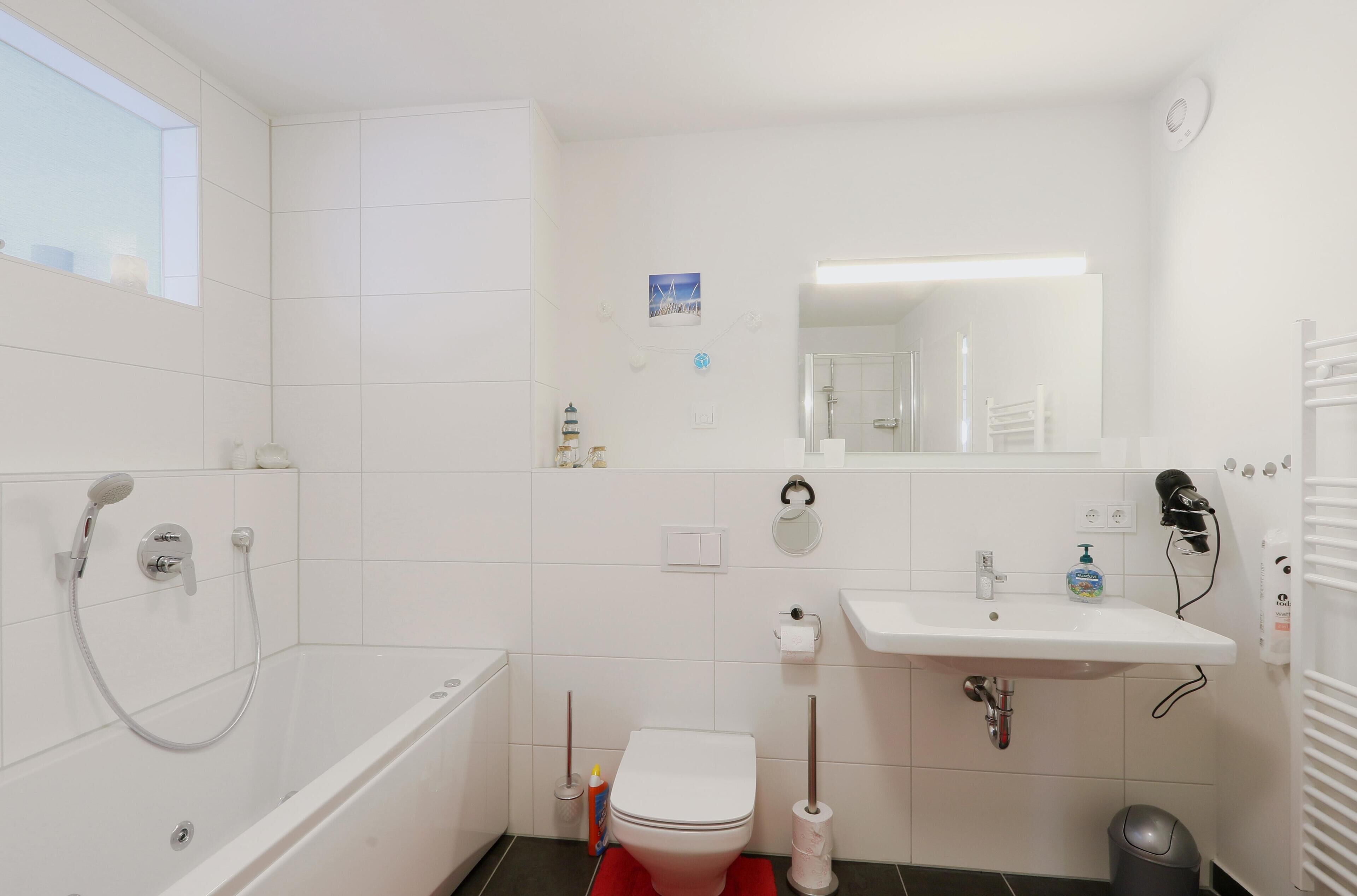 Une salle de bain moderne équipée d’une baignoire, de toilettes, d’un lavabo et d’un miroir.