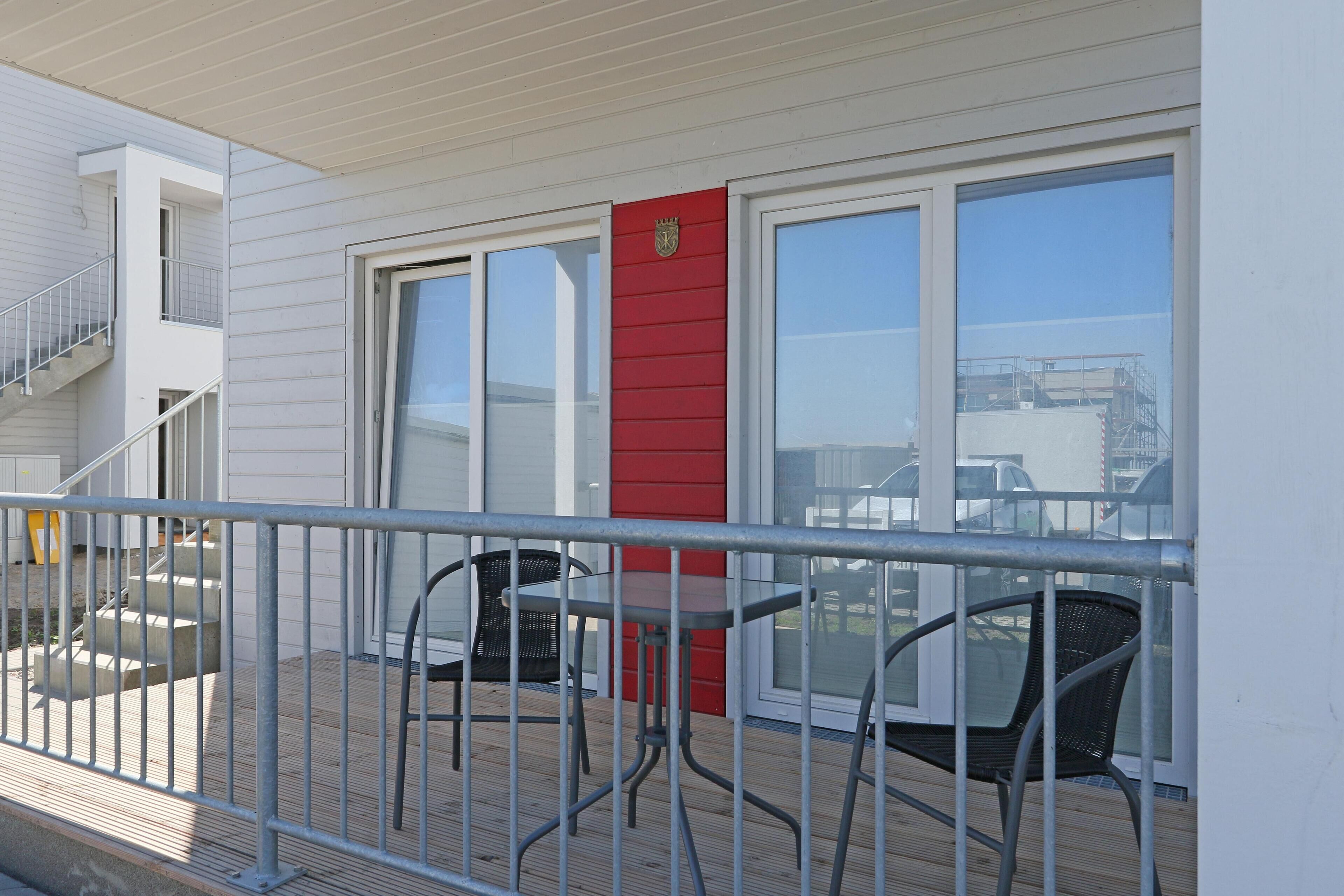 Un balcon avec une balustrade en métal, une table et deux chaises.