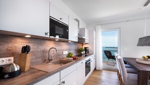 Una cocina moderna con armarios blancos, encimera de madera y vistas al exterior.