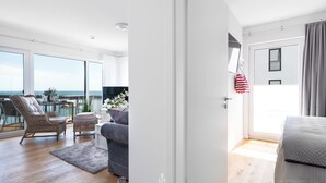 Un moderno salón con balcón, muebles de mimbre y vista al mar.