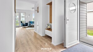 Un intérieur moderne avec un plancher en bois, une porte blanche et une vue sur un espace extérieur.