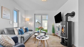 Un salon moderne avec un canapé gris, une table basse ronde, une cheminée et un téléviseur fixé au mur.