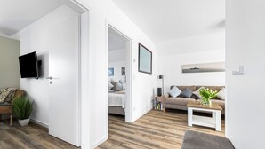 Uma sala de estar moderna com um sofá, mesa de centro e TV de tela plana na parede.